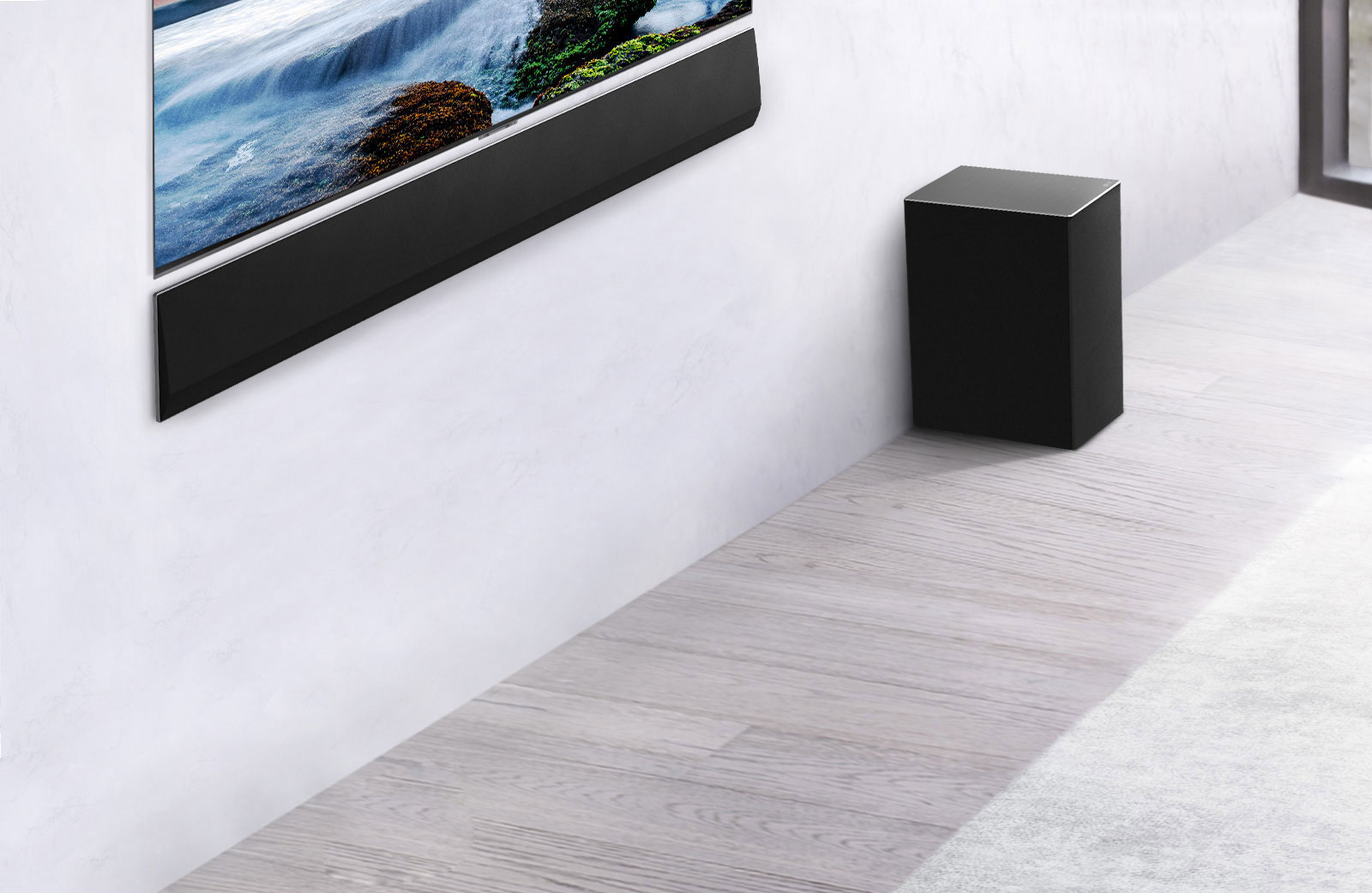 The TV and LG Soundbar are wall-mounted with a sub-woofer below and to the right. The TV shows a sunset at sea.